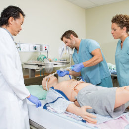 a doctor with two nurses practicing on a mannequin